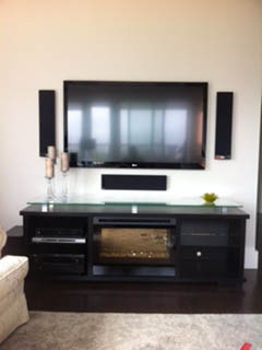 TV flanked by two slim wall speakers with a centre speaker below