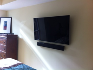 TV and soundbar mounted on a bedroom wall