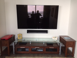 Large TV with a Sonos soundbar above a glass media stand