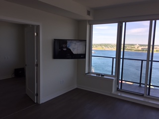 TV mounted beside floor-to-ceiling windows looking over the water