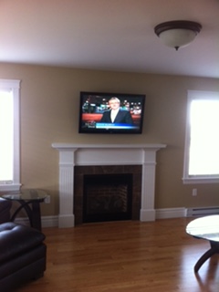 TV mounted above a fireplace between two windows