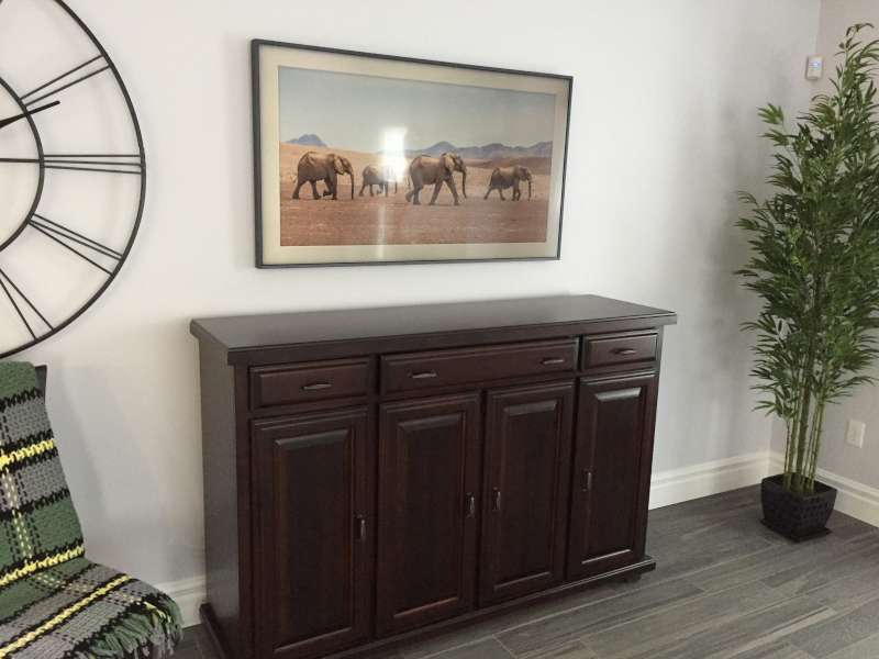 Frame TV showing an elephant photograph above a dark wood sideboard