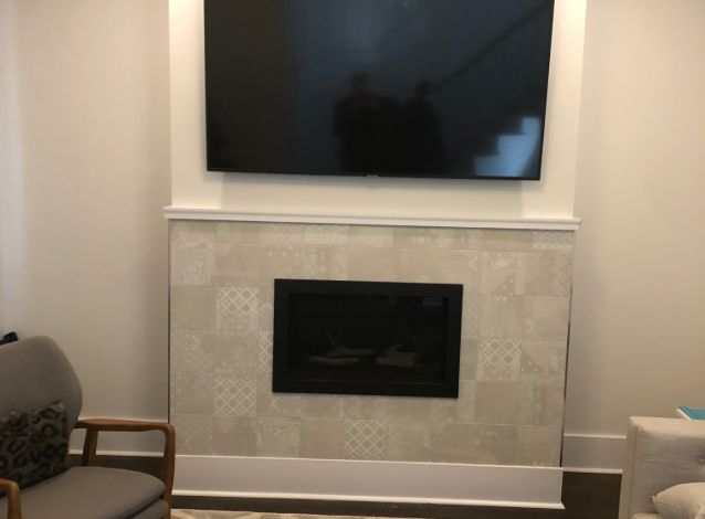 Large TV mounted above a patterned tile fireplace surround