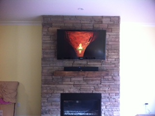 TV and soundbar mounted on a stacked-stone fireplace